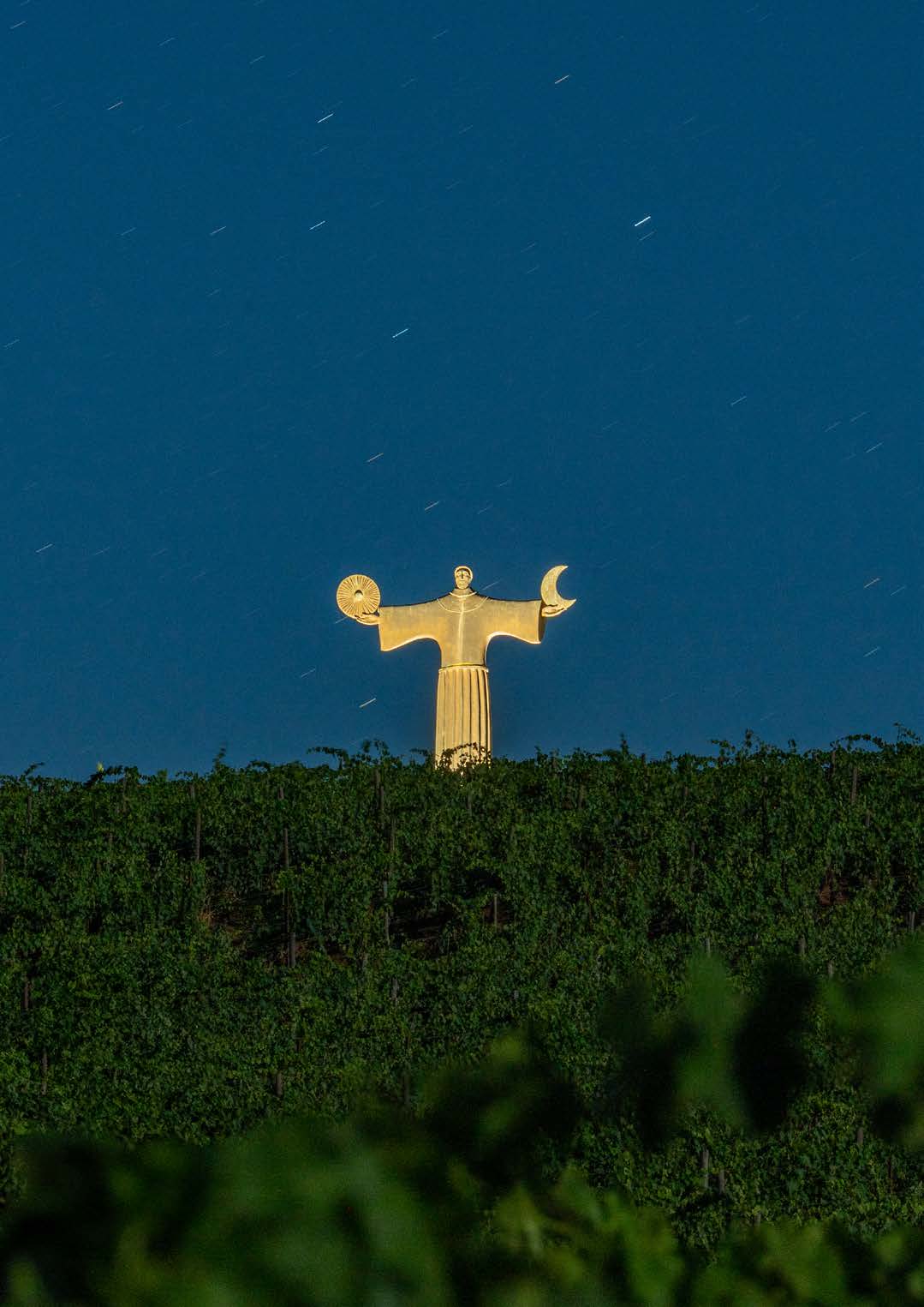 The golden Italo Zuffi sentinel sculpture on the vineyard ridge at dusk